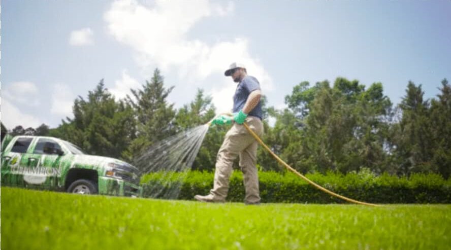 Champion Green technician applying liquid lawn treatment on customer property